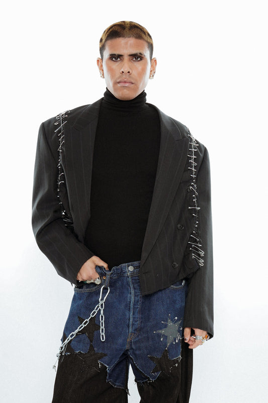 Person wearing a black jacket and star-patterned pants on a white background