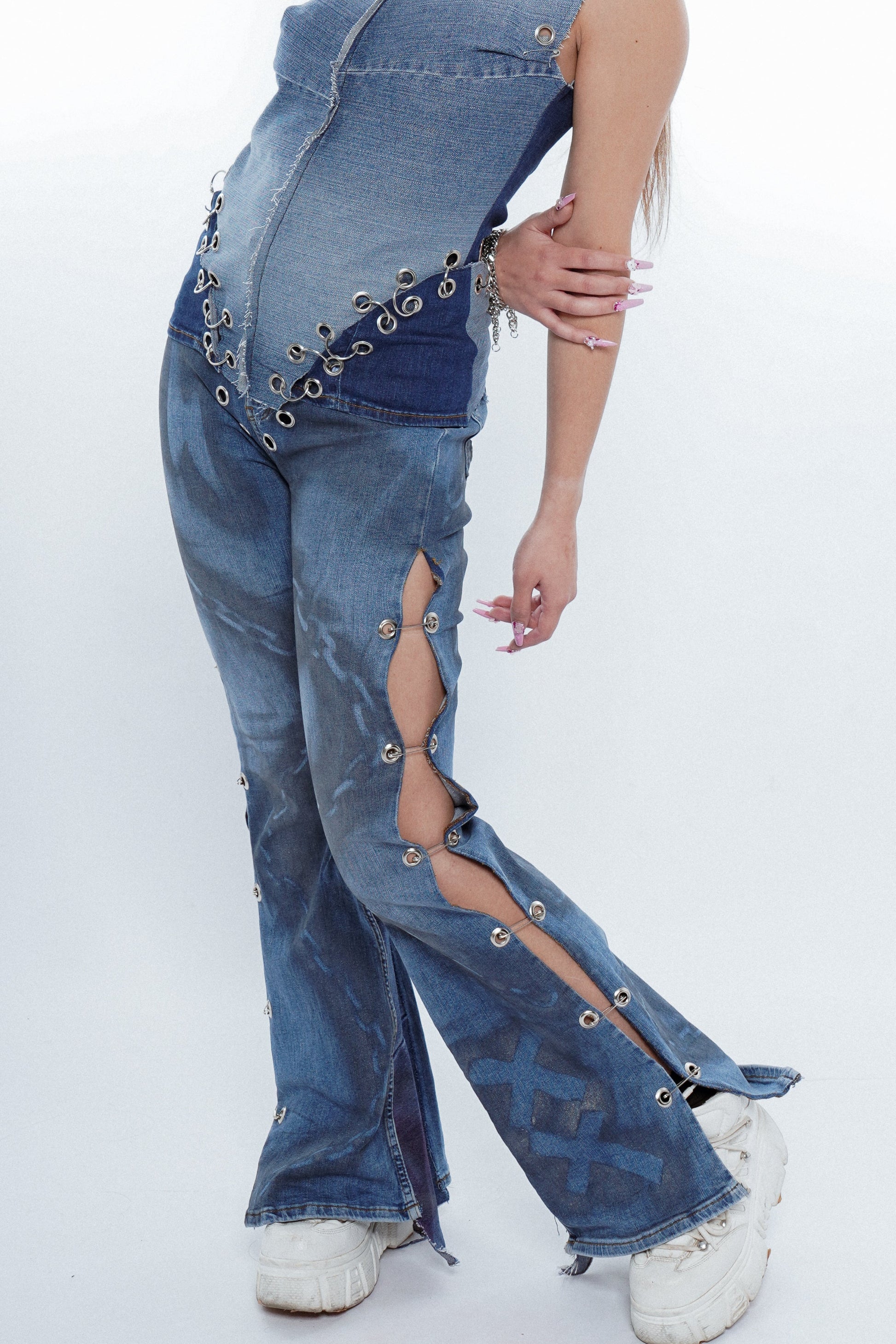 Person wearing a denim outfit with cut-out design on a white background