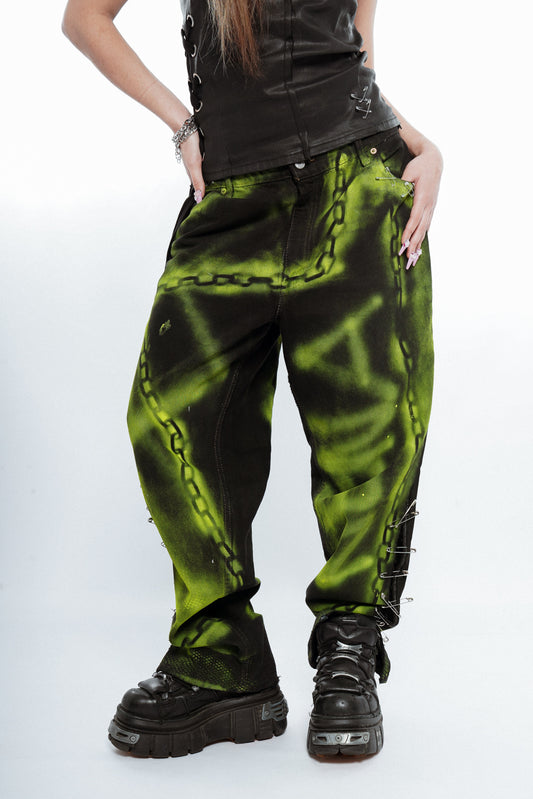 Person wearing green and black tie-dye pants with chain details on a white background